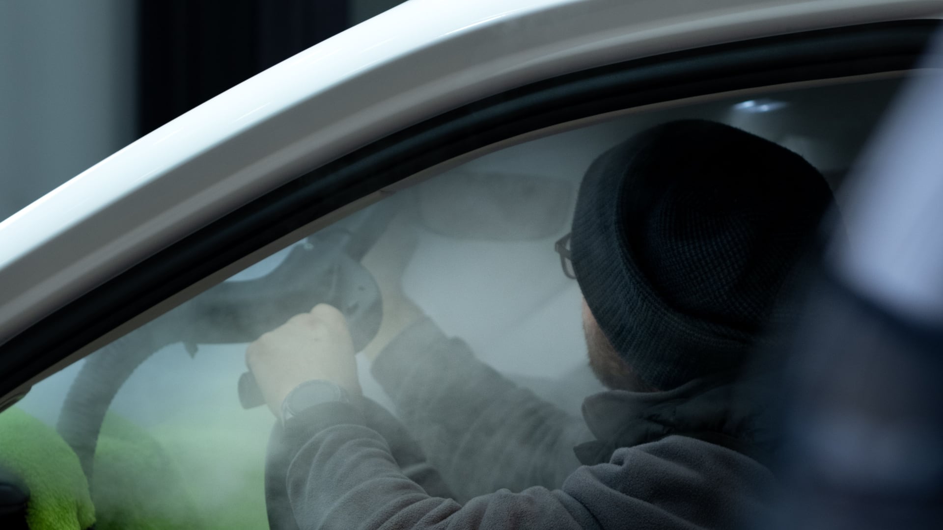 A professional using steam equipment inside a vehicle